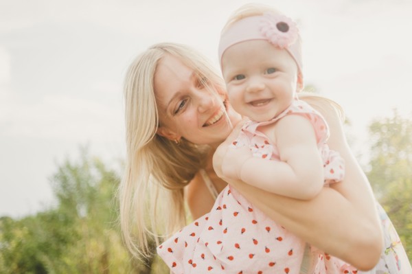 Mother hugging baby daughter on sunny day