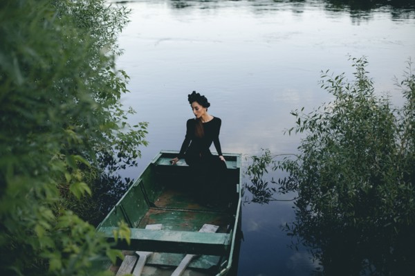 Middle Eastern woman wearing black dress in boat on lake