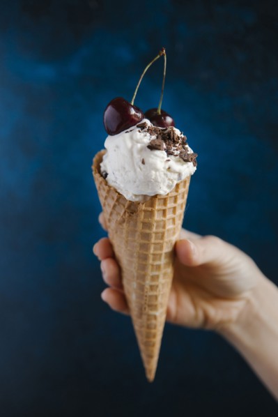 Hand holding ice cream cone with cherries