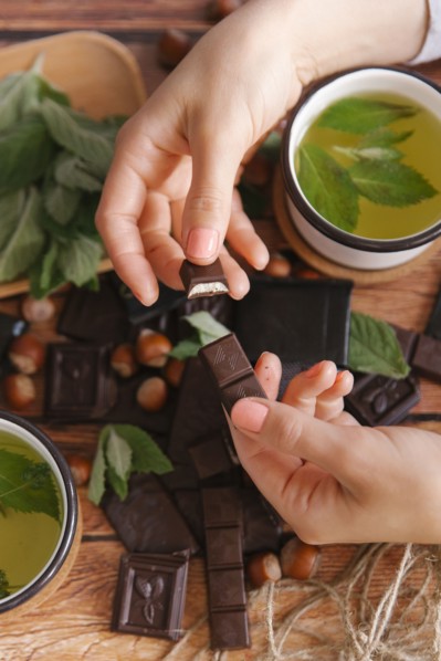 Hands of woman breaking chocolate near green tea
