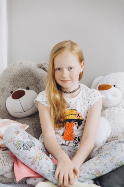 Smiling Middle Eastern girl sitting with large teddy bears