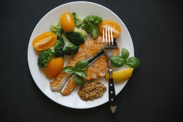 Cooked salmon on plate with broccoli and tomatoes