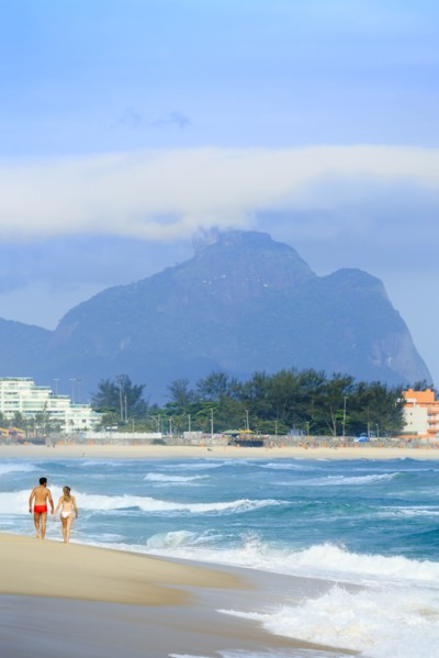 Couple walking on beach near waves
