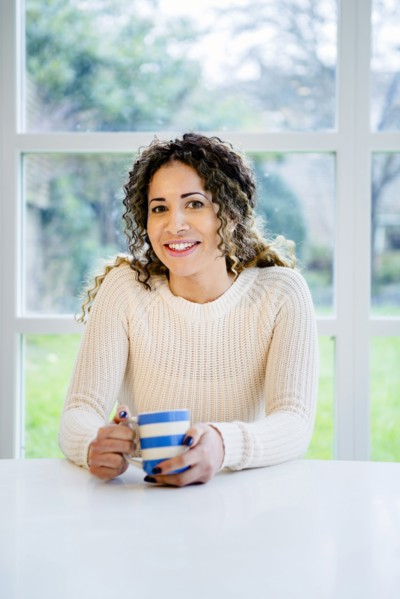 Smiling woman sitting at table holding coffee cup