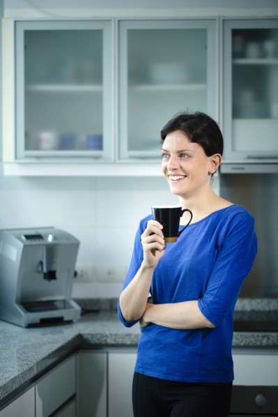 Smiling Caucasian woman drinking coffee in kitchen