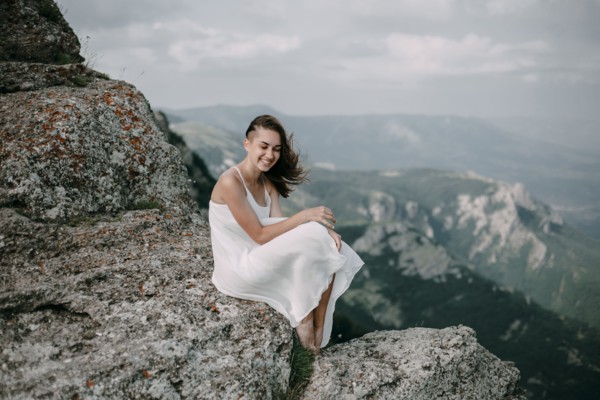 Smiling Caucasian woman sitting on rock overlooking landscape