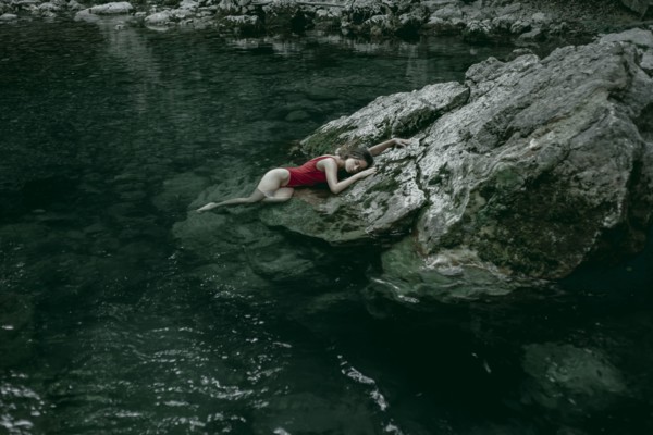 Caucasian woman laying on rocks in pool of water
