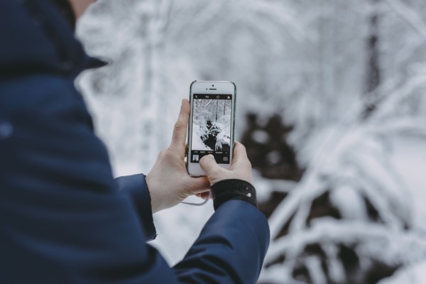 Caucasian woman photographing snow with cell phone