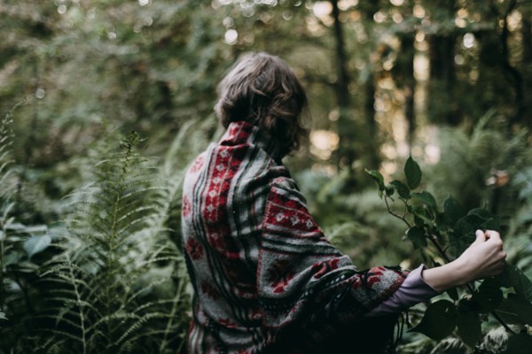 Caucasian woman holding green leaf in forest