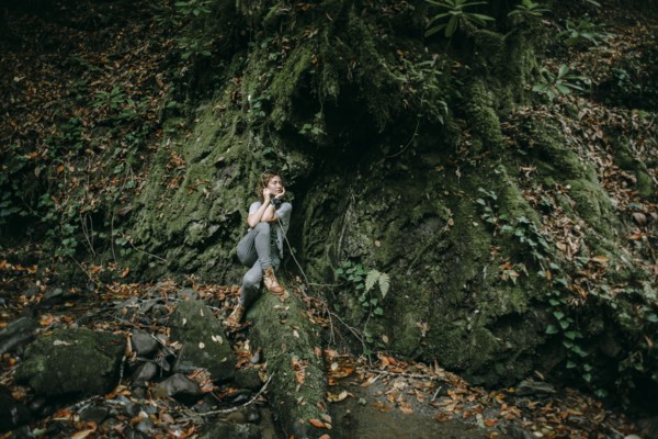 Caucasian woman sitting in forest holding branch