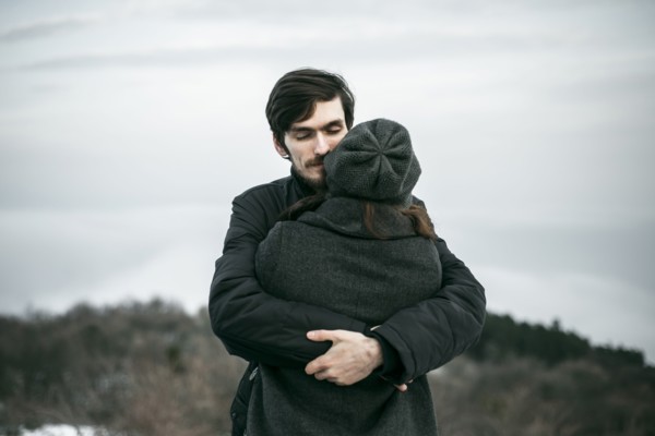 Caucasian couple hugging on hill