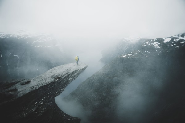Caucasian man on foggy cliff admiring scenic view of mountain river
