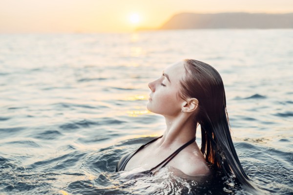 Caucasian woman swimming at sunset
