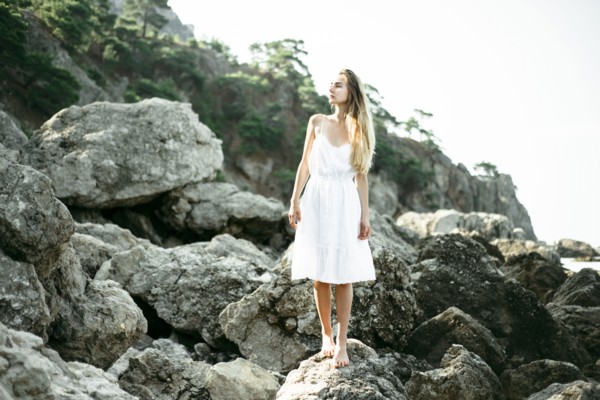 Caucasian woman wearing dress standing on rocks