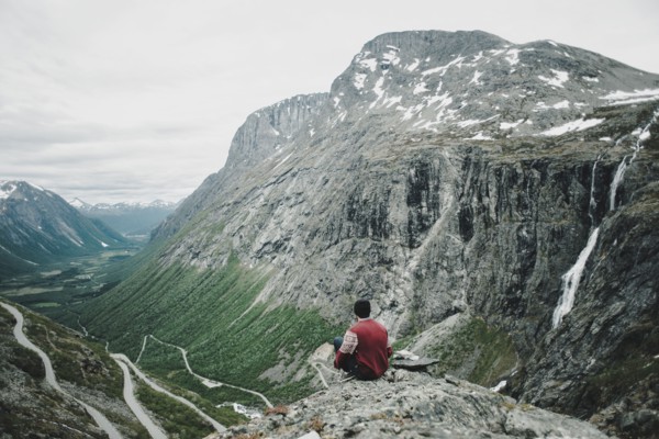 Caucasian man sitting on rock admiring scenic view of valley