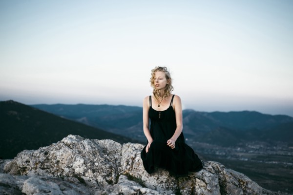 Caucasian woman sitting on rock near mountains