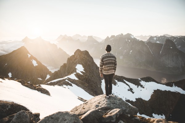 Caucasian man standing on rock admiring scenic view of mountain lake