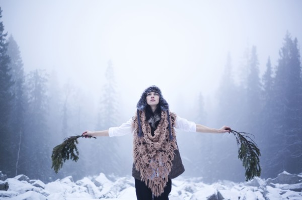 Caucasian woman holding tree branches in snowy woods