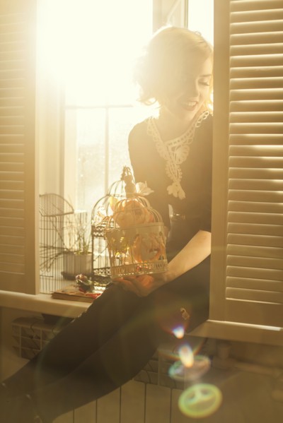 Caucasian woman holding birdcage in window