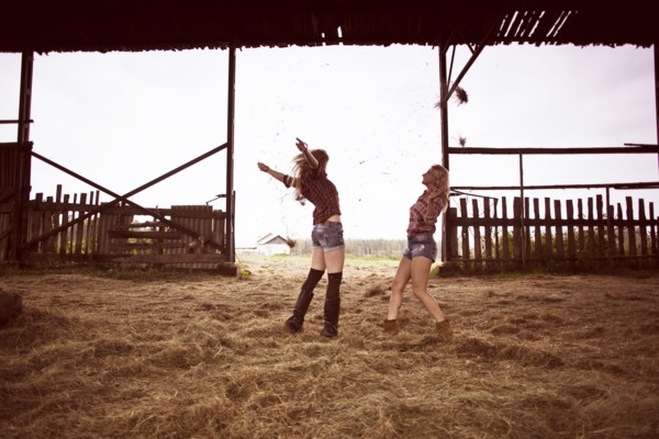 Caucasian women playing in hay in barn