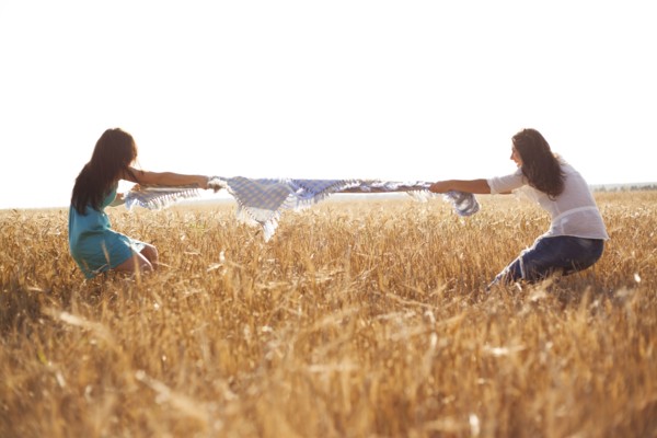 Caucasian women playing tug-of-war in rural field