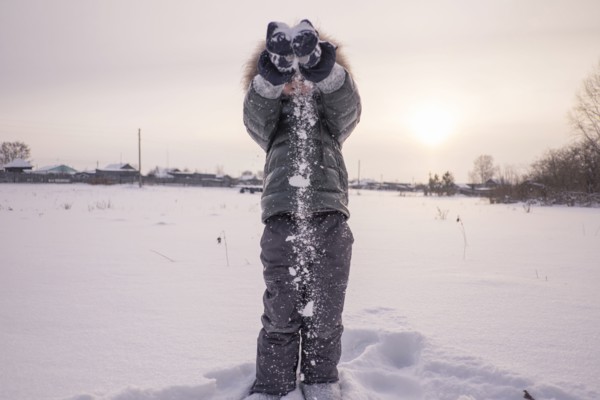 Mari boy in parka playing in snowy field