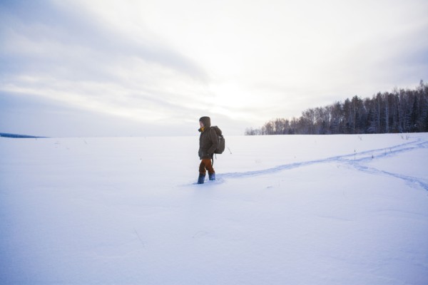 Mixed race man walking in snowy field
