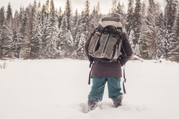 Mixed race man walking in snowy forest
