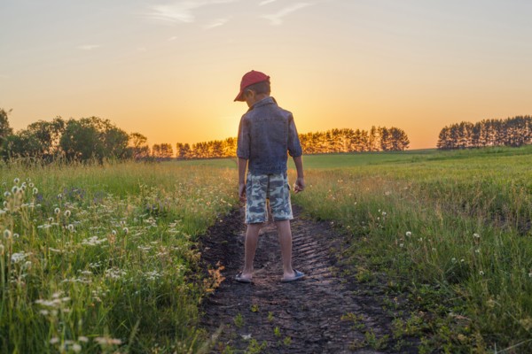 Mari boy standing in tire tracks in rural field