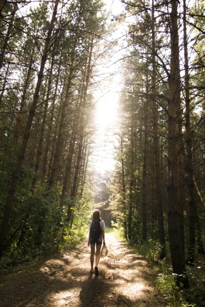 Caucasian woman walking on tree-lined forest path