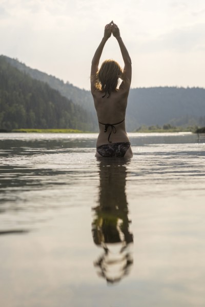 Caucasian woman standing in lake wearing bikini