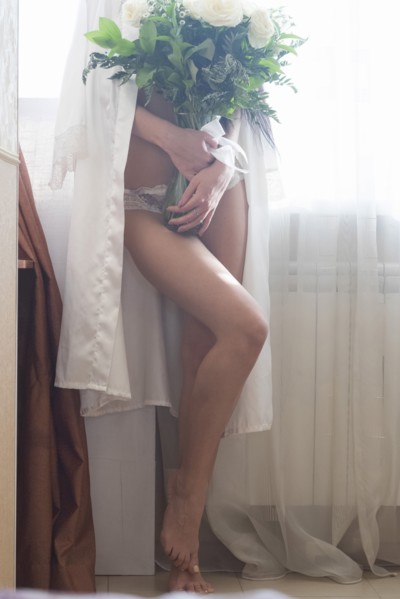 Caucasian woman wearing lingerie holding vase of flowers