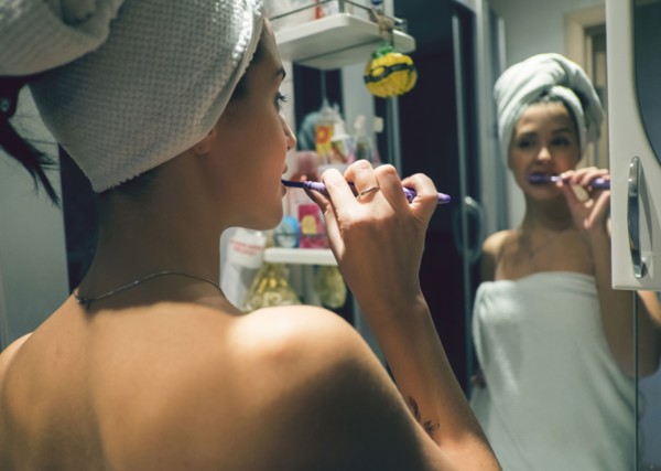Caucasian woman brushing teeth in mirror