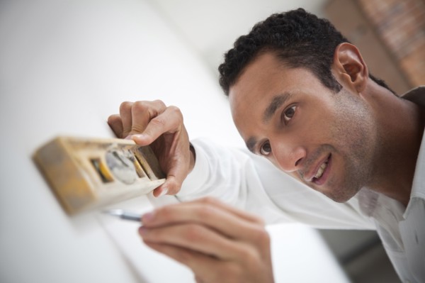 Hispanic carpenter using level on wall