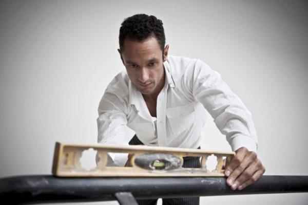 Hispanic man using level on railing