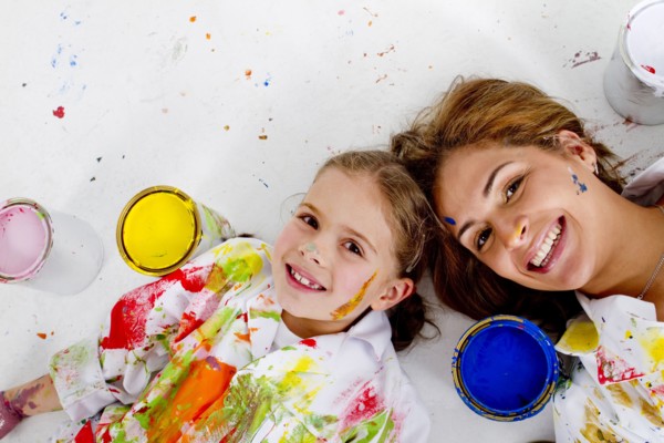 Hispanic mother and daughter covered in paint laying on floor