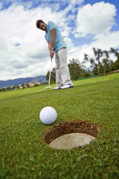 Hispanic man putting golf ball