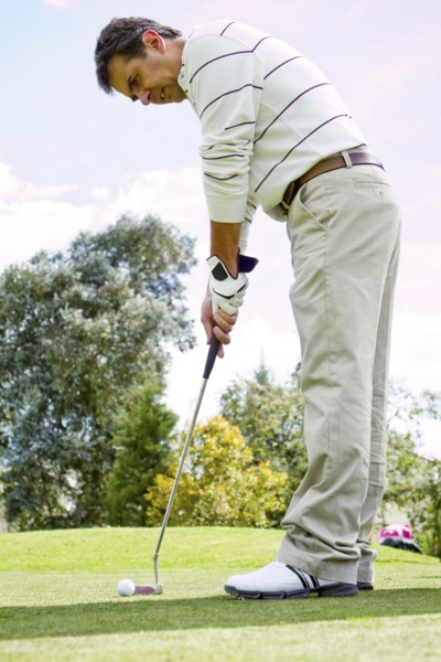 Hispanic man putting golf ball