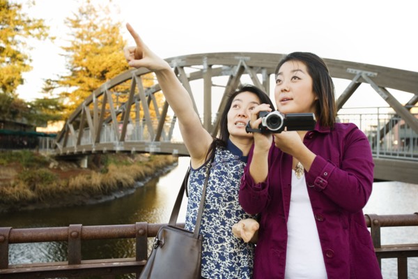 Chinese mother and daughter taking photographs outdoors