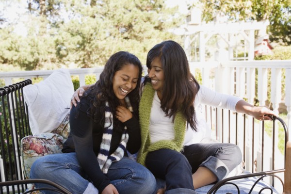 Hispanic teenager and woman laughing on porch