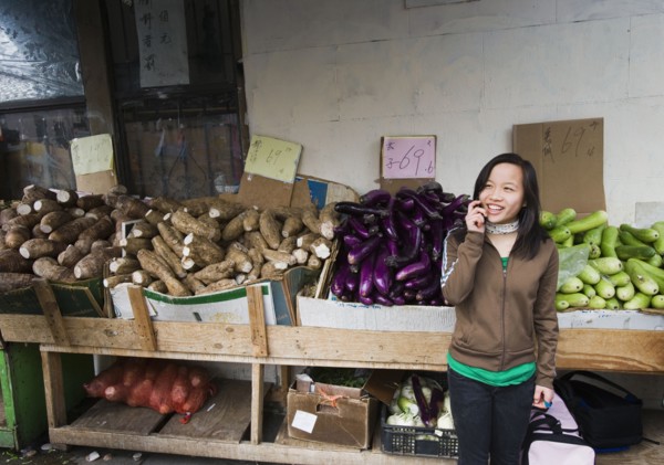 Chinese girl talking on cell phone at outdoor market
