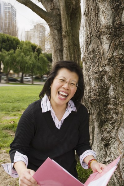 Chinese woman holding folder next to tree