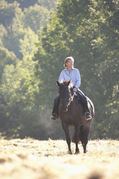 Caucasian woman riding horse in field