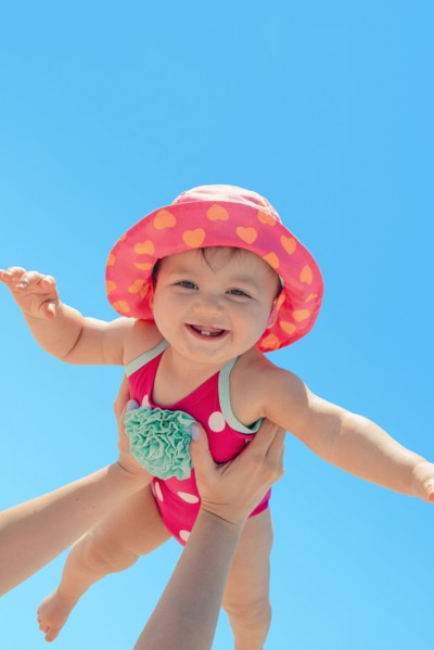 Woman holding baby girl against blue sky
