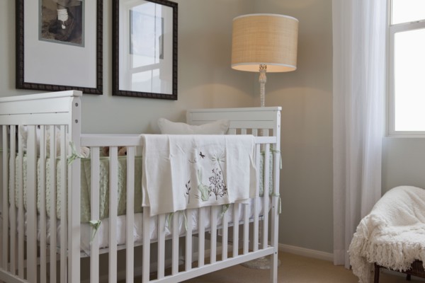 Baby's crib with floor lamp and picture frames in the house