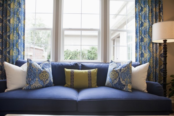 Close-up of cushions on blue couch against window in the living room at home