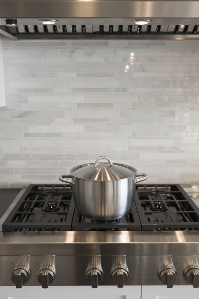 Sauce pan on stove against backsplash in kitchen