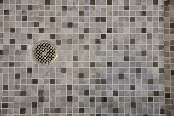 Close-up of drain in mosaic tile floor in the bathroom at home