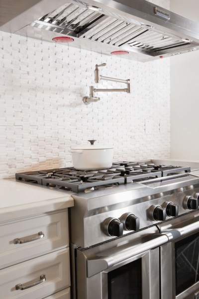 Kitchen with double oven gas stove below vent hood at home