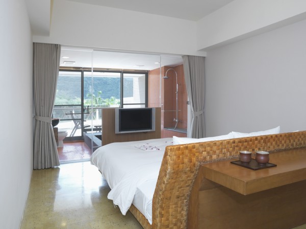 Small modern bedroom with glass wall separating from bathroom